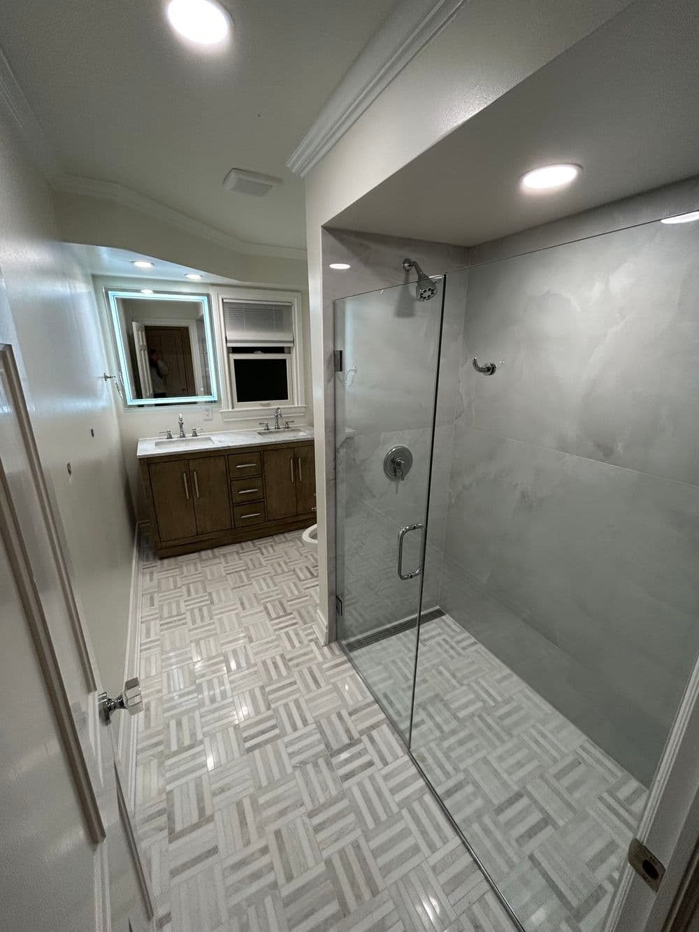 Modern bathroom with a glass shower, stylish vanity, and elegant tiled floor.