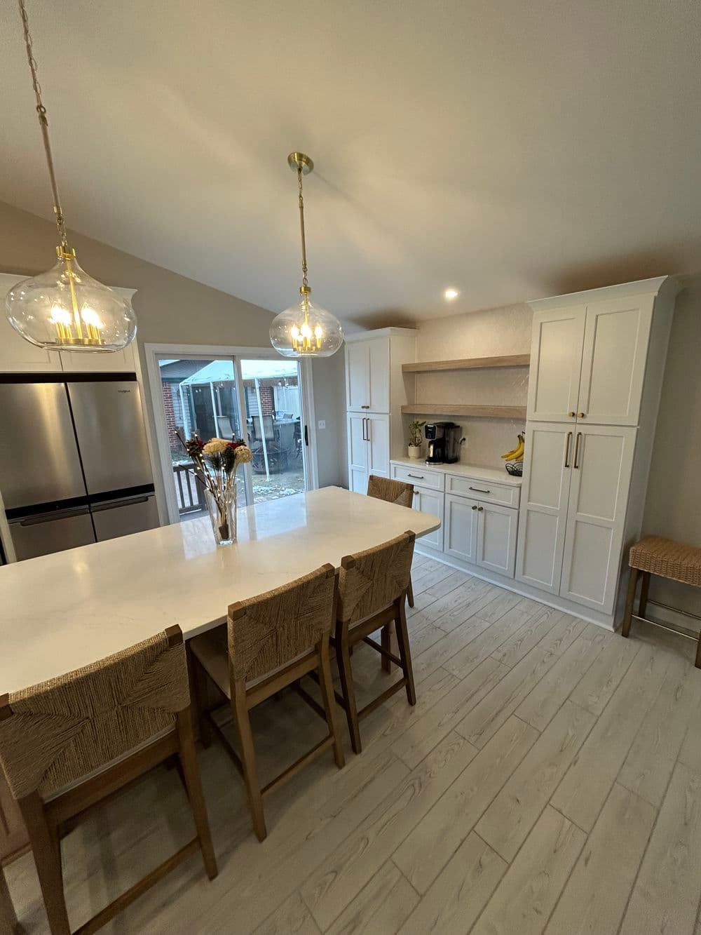 Modern kitchen with white cabinets, large island, and pendant lights, featuring a bright, airy design.