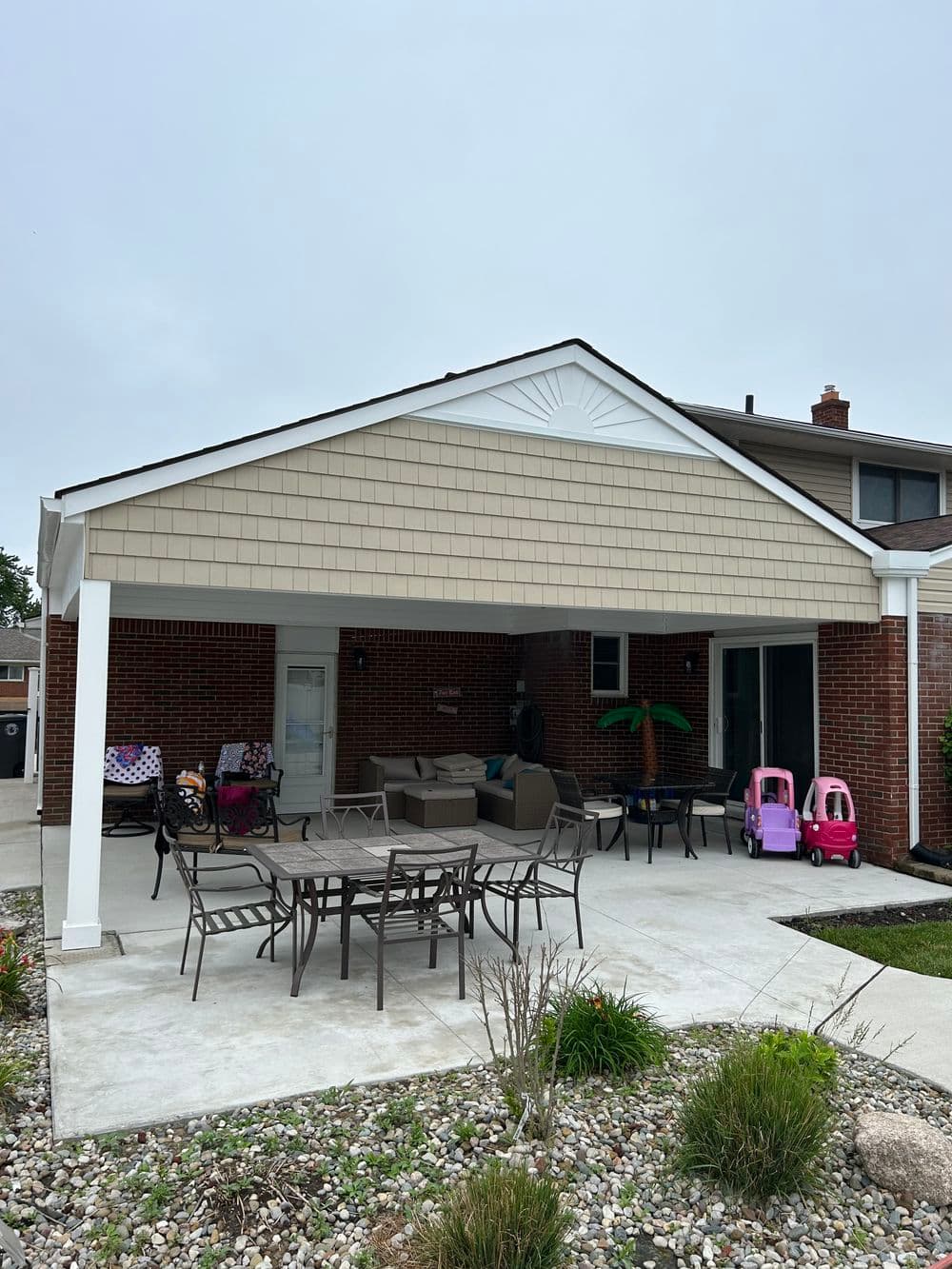 Covered patio with seating area, children's toys, and landscaped garden in a residential backyard.